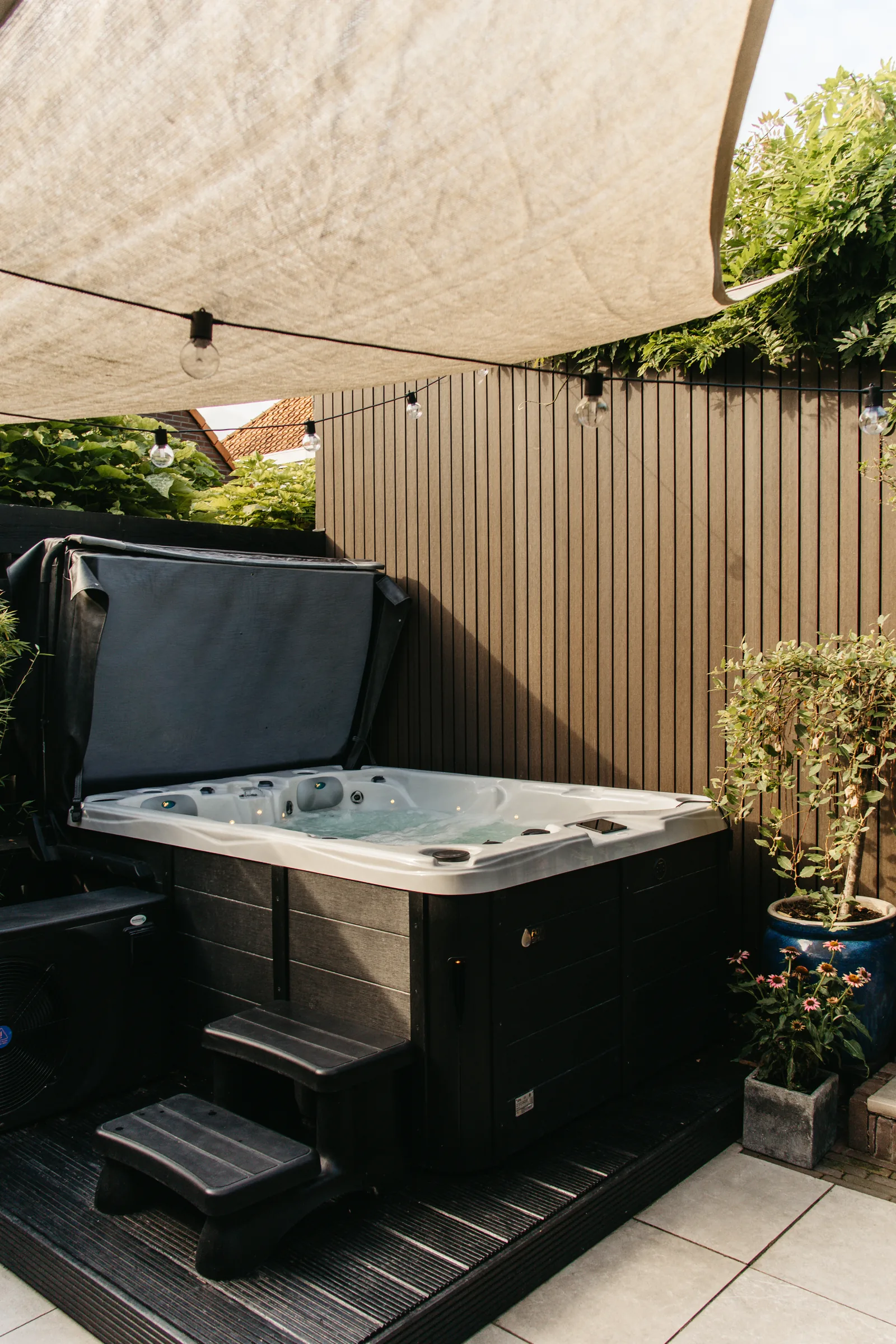Privéjacuzzi op het terras met zonnescherm en sfeerverlichting